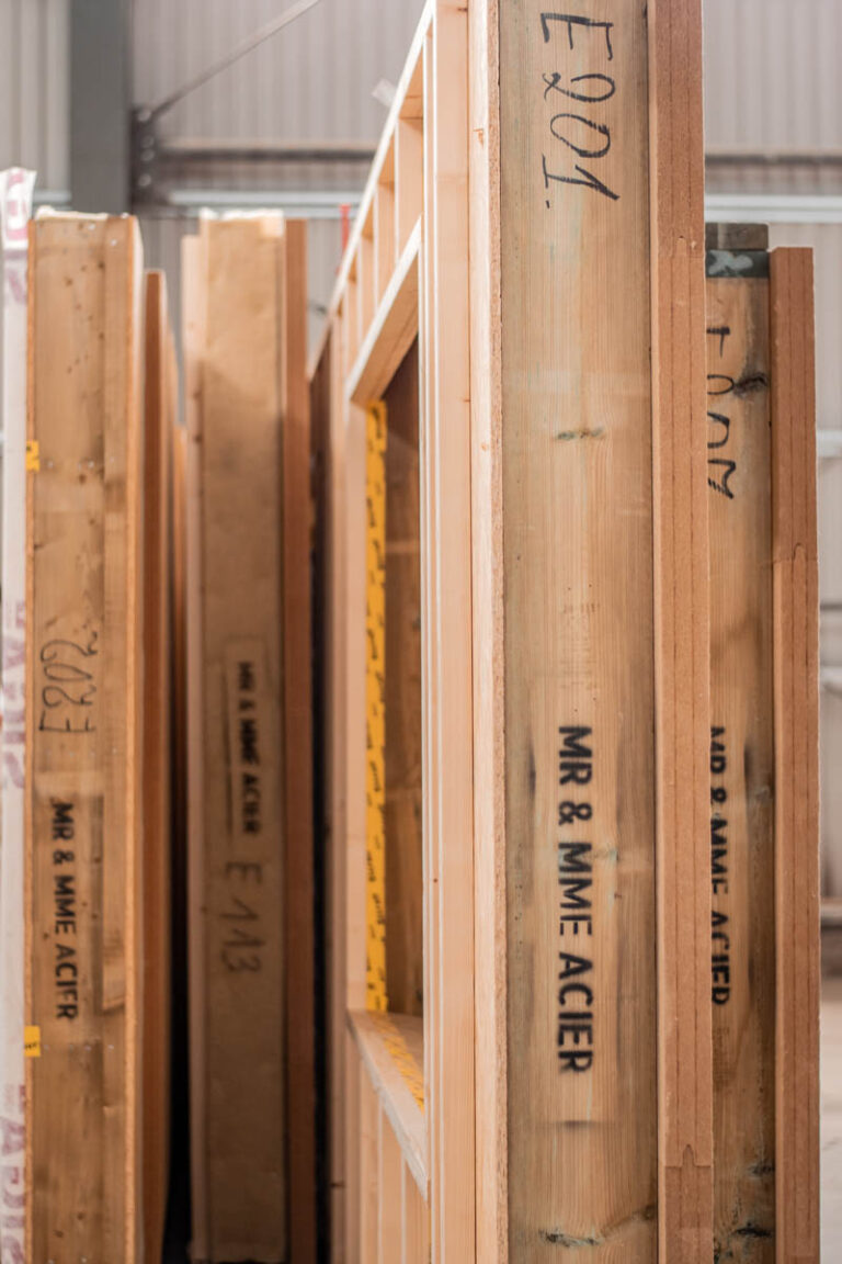 as Bild zeigt verschiedene Holzwände, die in der Produktion von Xylotec gelagert werden, um später damit ein Massivholzhaus im Raum Köln in NRW zu bauen.