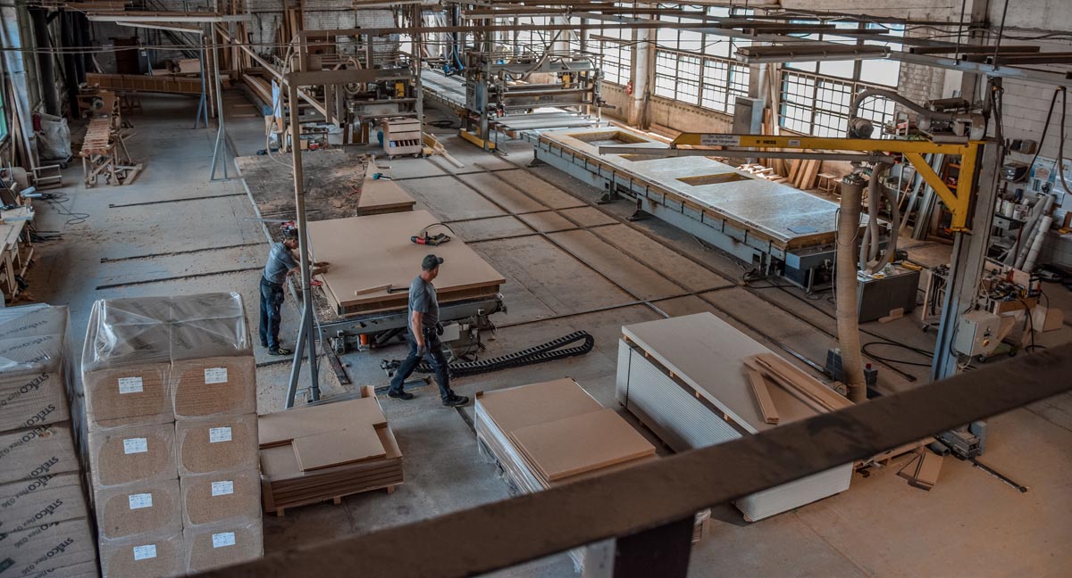 Bild der Lagerhalle der Firma Xylotec in der Nähe von Köln mit großen Maschinen für den Zuschnitt der Holzwände für das Fertighaus.